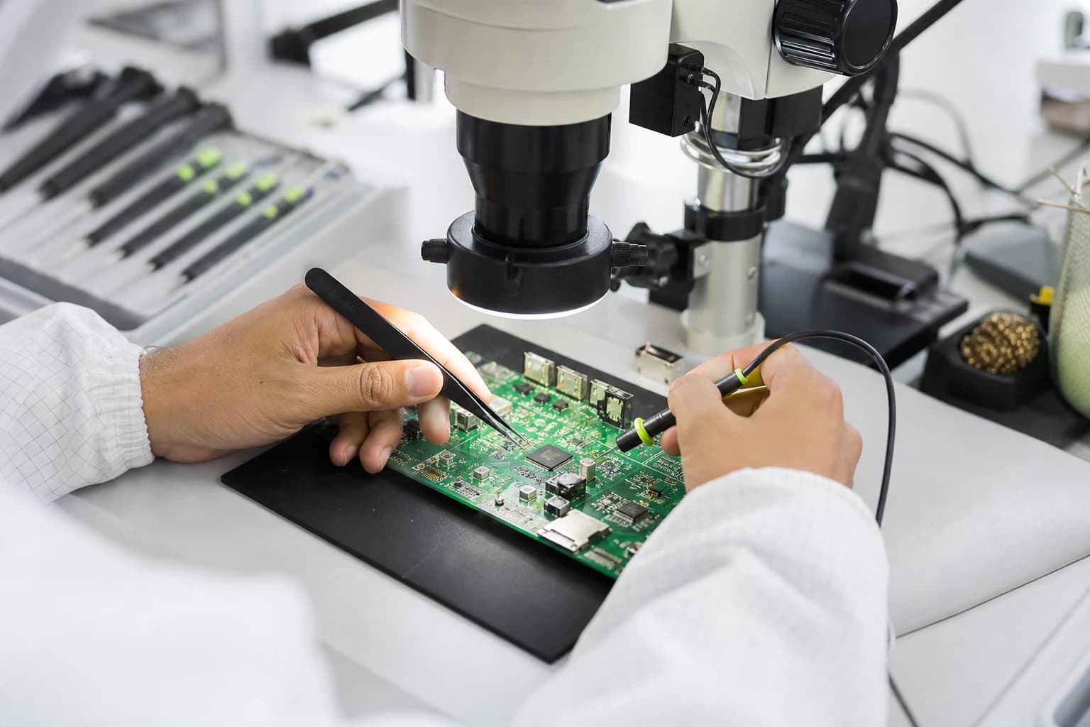 Engineer inspecting a populated circuit board under a precision microscope
